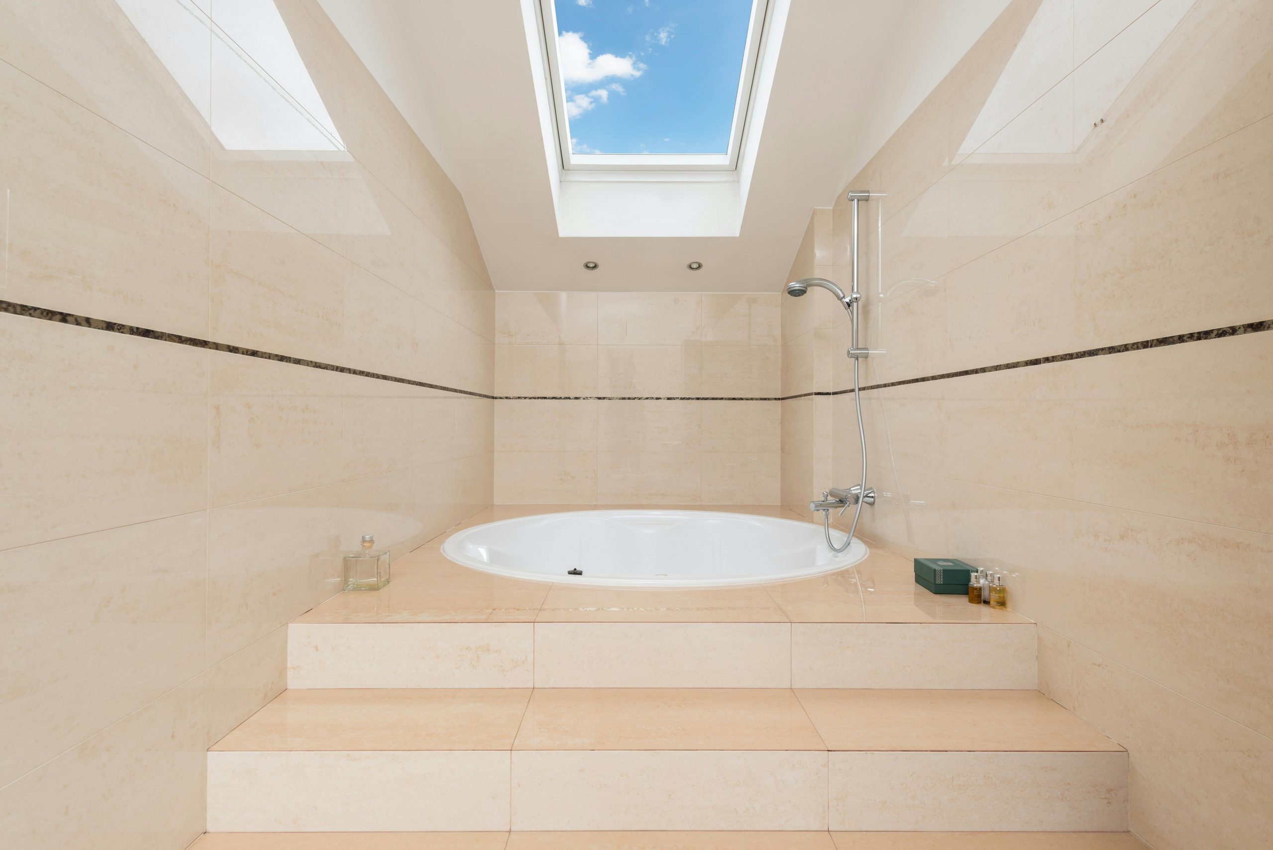 bathtub with steps under a skylight